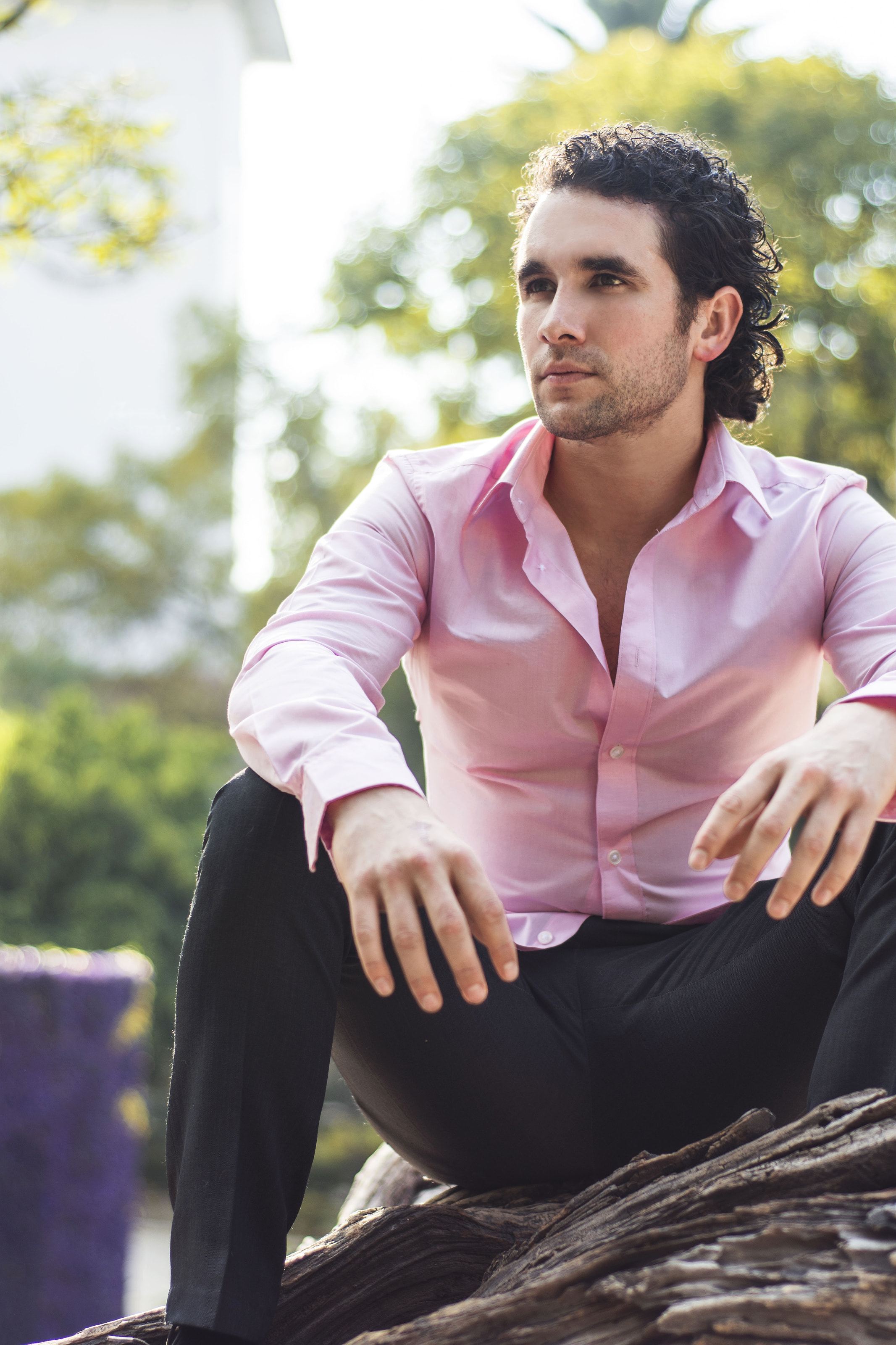 Marco Valdés con camisa rosa, sentado al aire libre